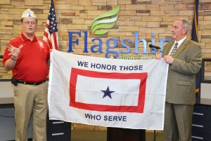 Frozen Transportation - A veteran and businessman at Flagship holding a "We Honor Those Who Serve" banner