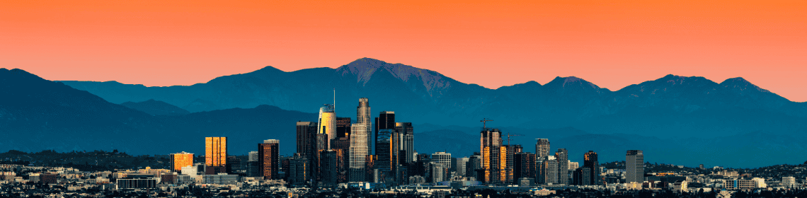 Image of the Los Angeles skyline at sunset with an orange sky and mountains in the background, representing Palisades Logistics order fulfillment and warehouse services.